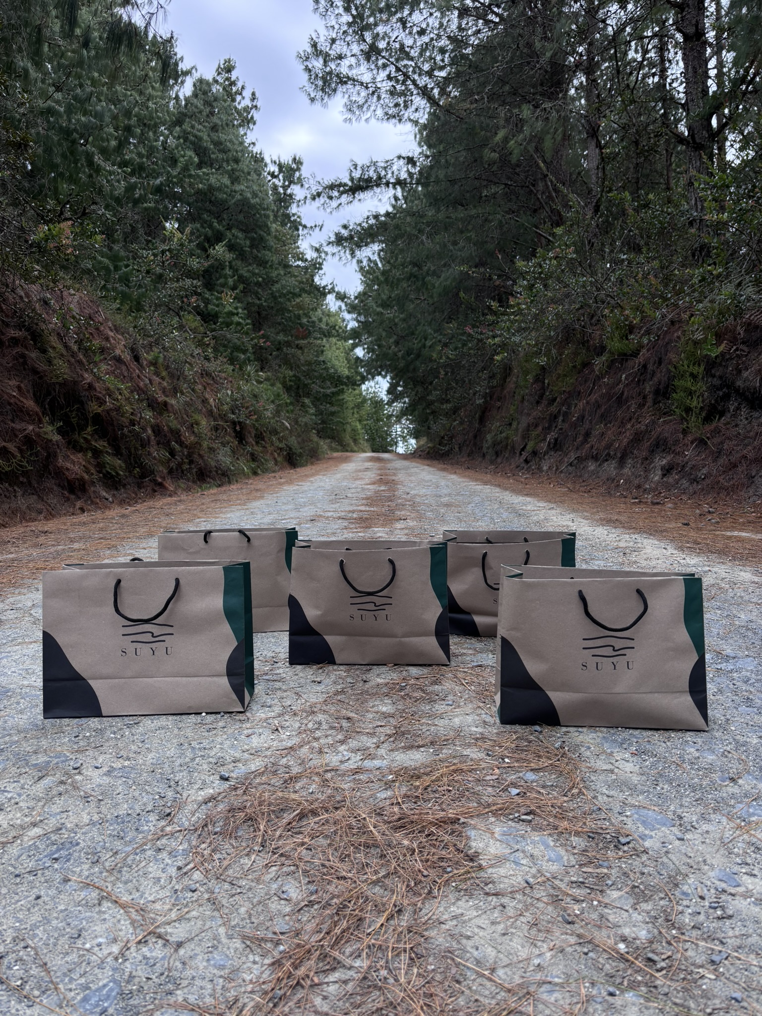 Fundas de papel con la marca SUYU en un camino de bosque